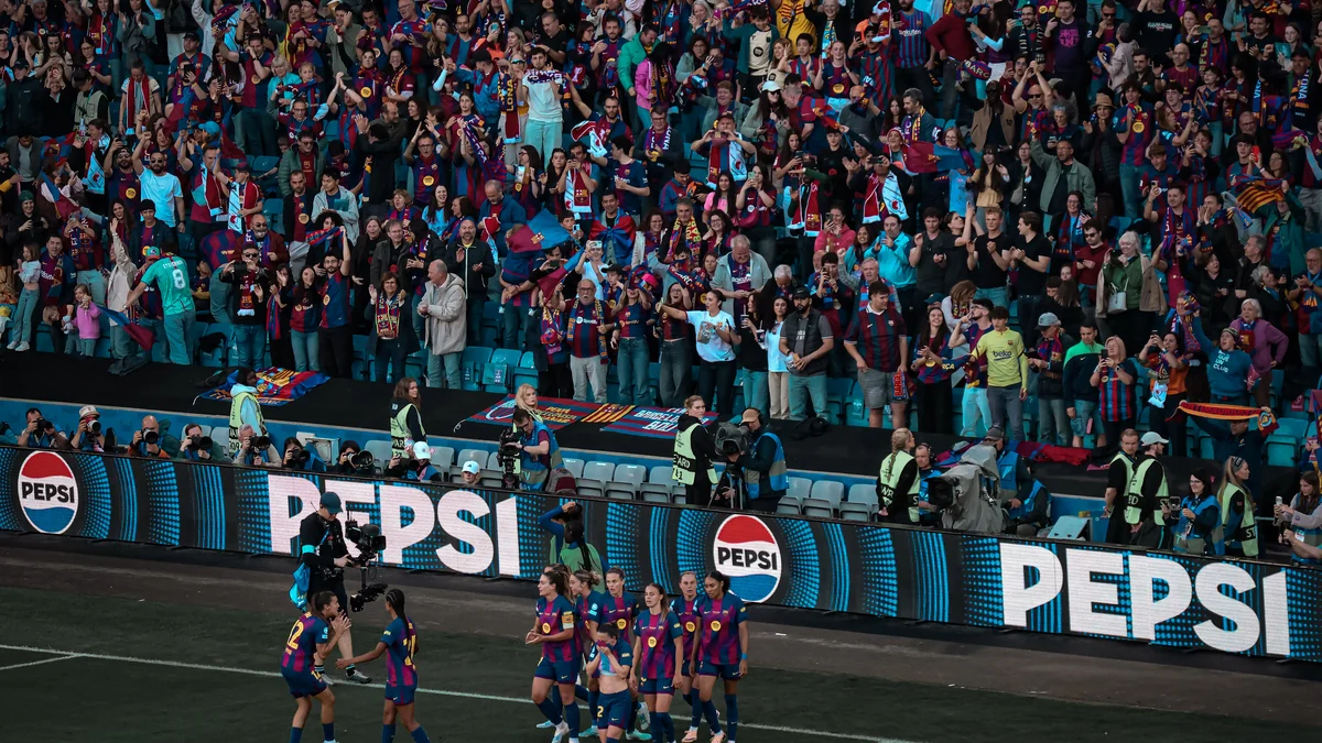 Barcelona players gathered beside the pitch in front of a packed stand