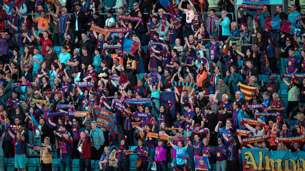 Barcelona supporters raise blue and claret scarves in a crowded stand