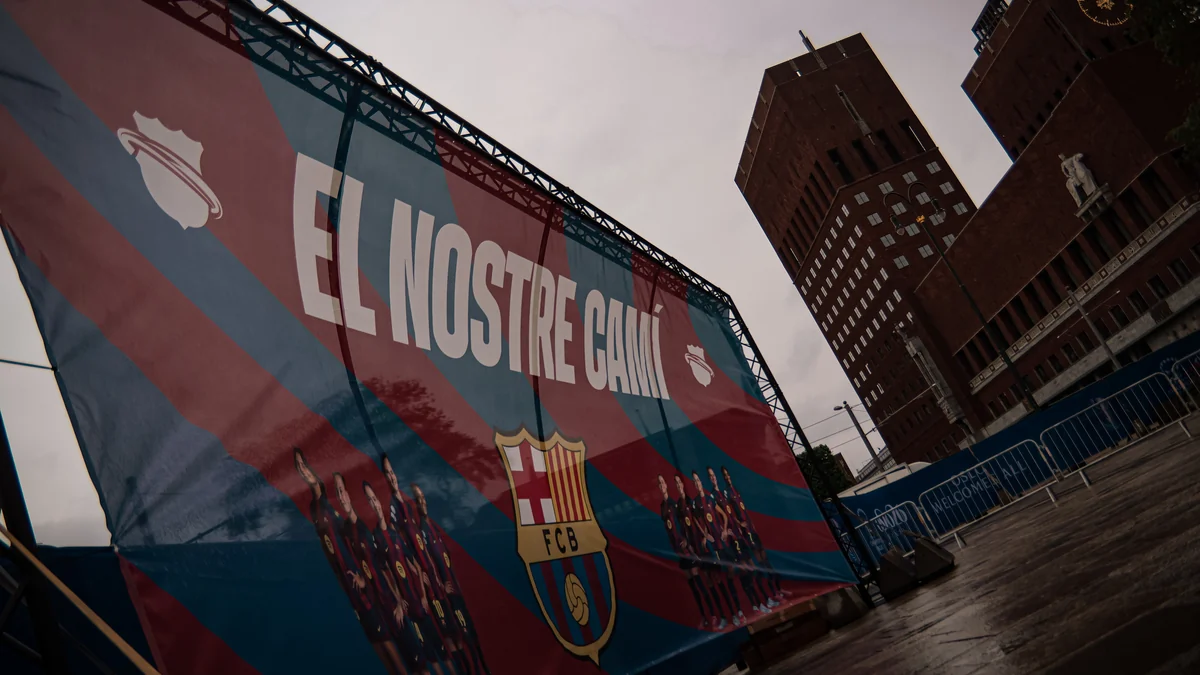 Large blue and claret Barcelona banner in front of brick buildings under an overcast sky