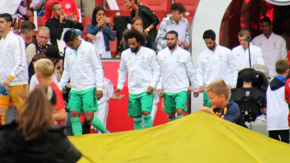 Courtois et des joueurs du Real Madrid, en veste blanche et short vert, entrent sur le terrain