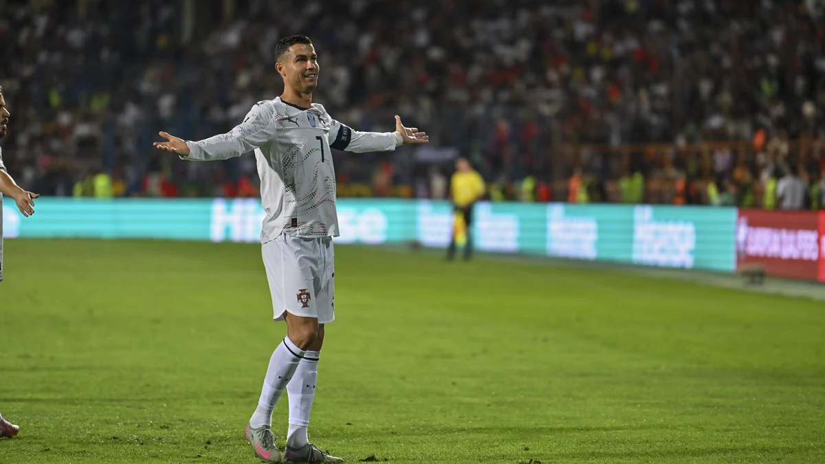 Cristiano Ronaldo abre os braços no gramado usando a camisa branca número 7 de Portugal