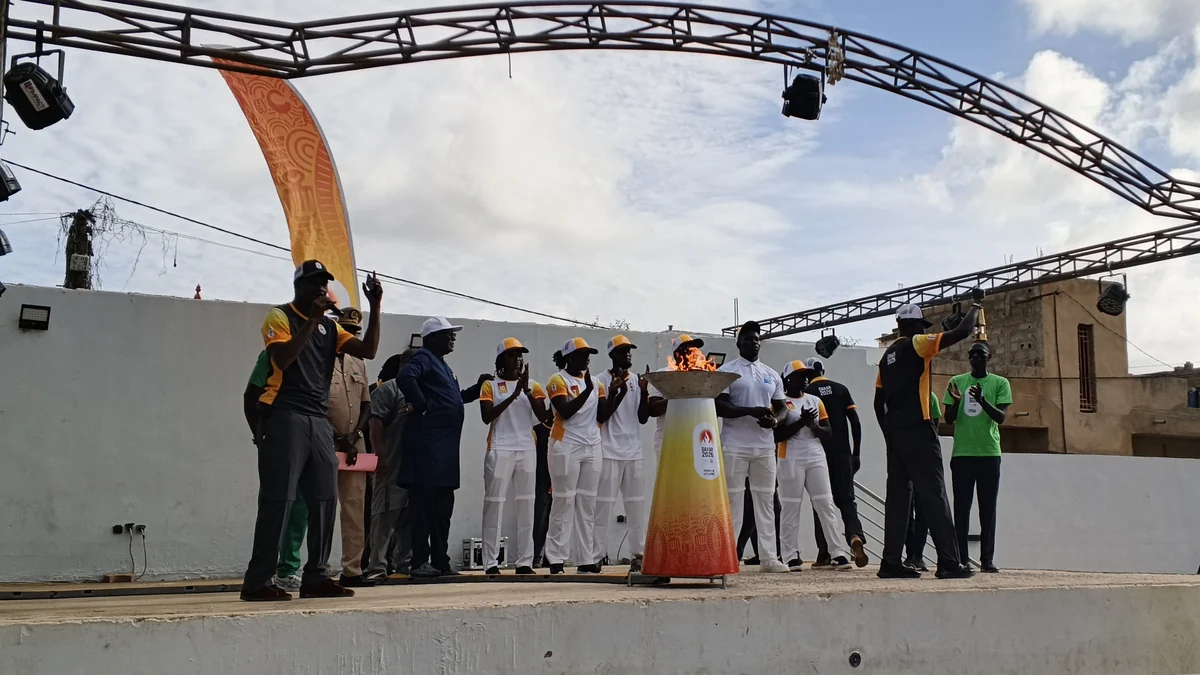 Groupe réuni sur une scène autour de la flamme de Dakar 2026