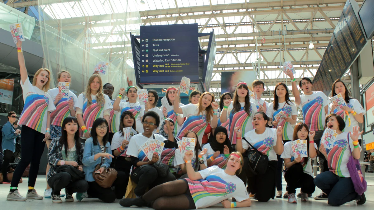 Grupo de fãs de K-pop com camisetas coloridas posa dentro de uma estação