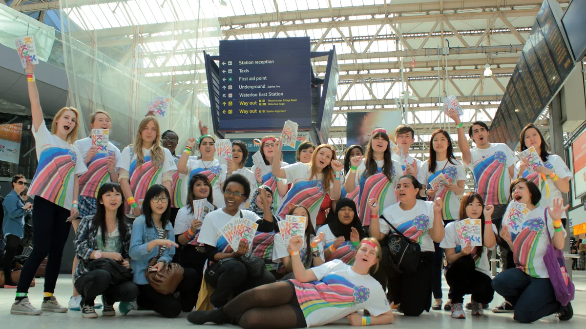 Groupe de fans de K-pop en t-shirts colorés posant dans une gare