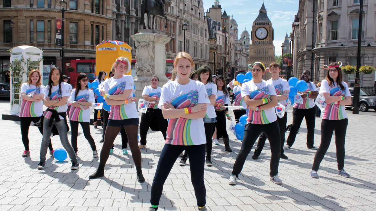 Grupo com camisetas iguais dança em formação numa praça de Londres