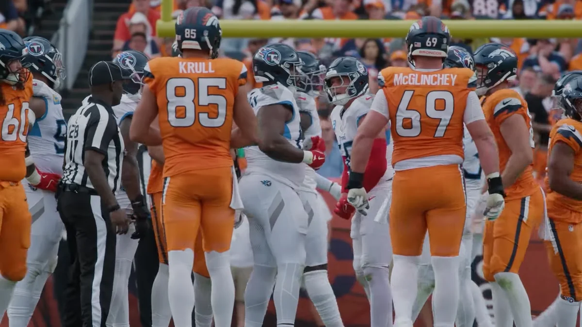 Jogadores dos Broncos e dos Titans reunidos em campo perto de um árbitro