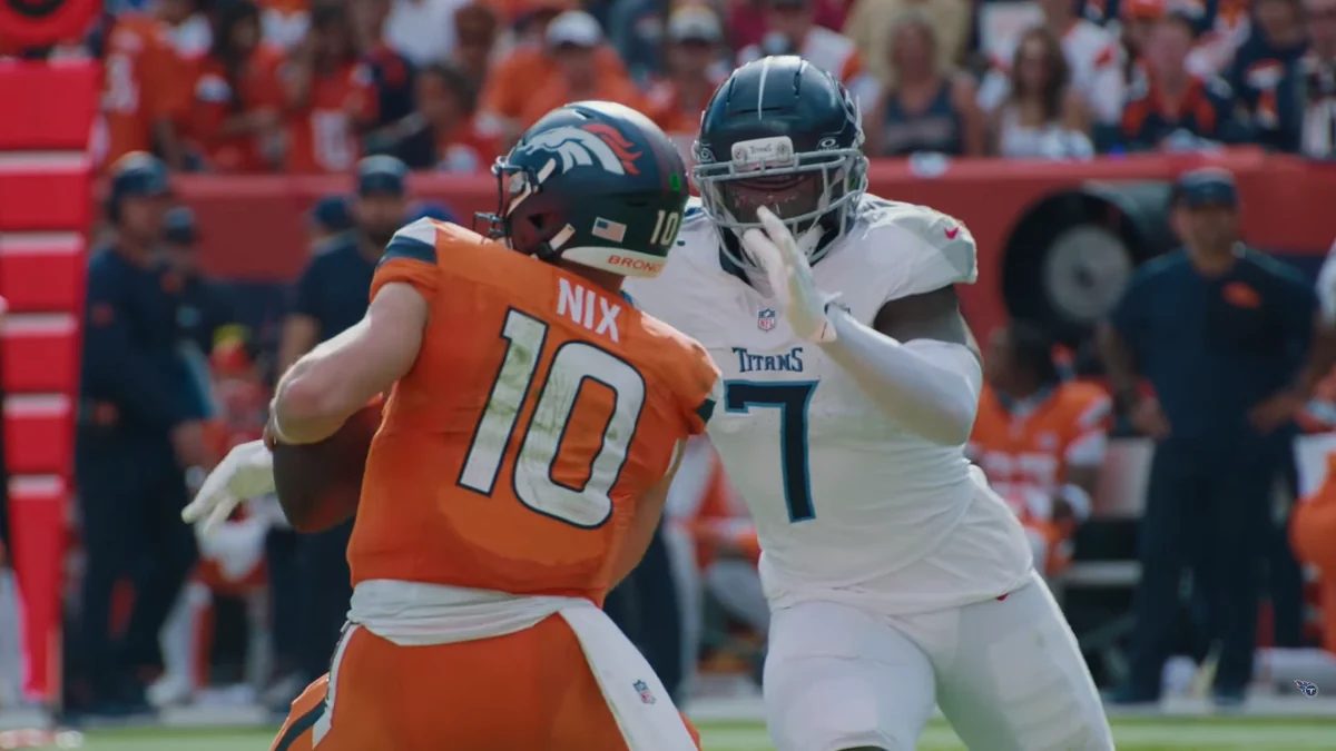 Jogador dos Denver Broncos com camisa laranja bloqueia adversário dos Tennessee Titans