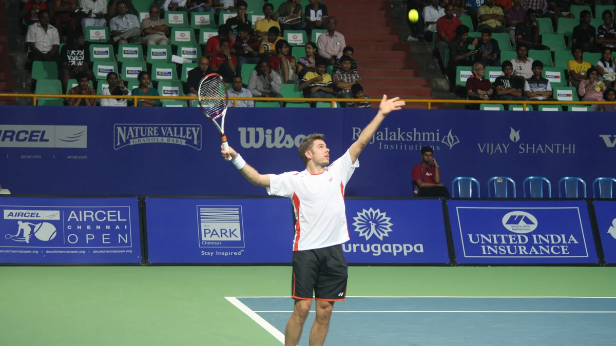 Stan Wawrinka extends his arm to toss the ball during a serve on a tennis court.