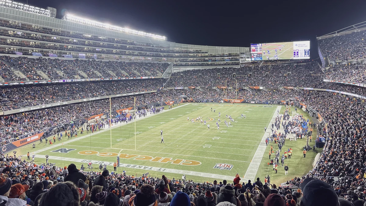 Football field illuminated at night and surrounded by packed stands