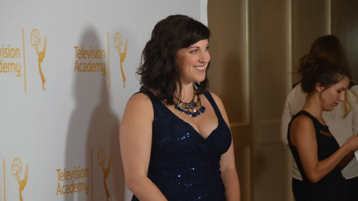 Mujer con vestido azul ante un panel de la Television Academy en una recepción