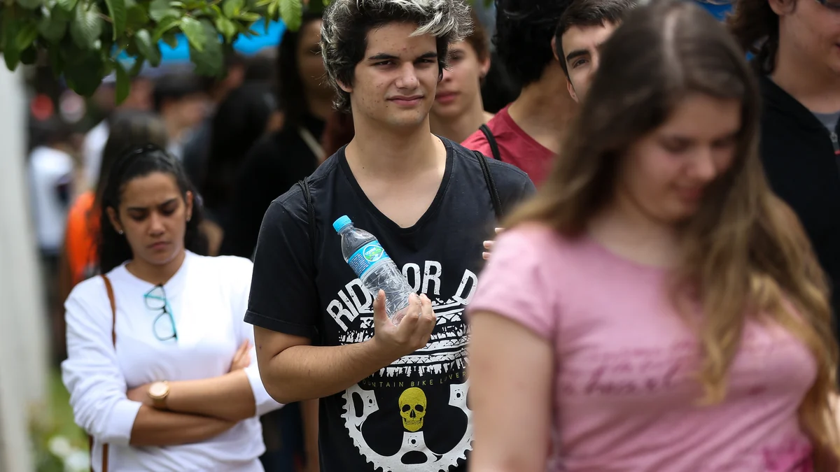Jeunes dans une file, avec au centre un garçon tenant une bouteille d’eau