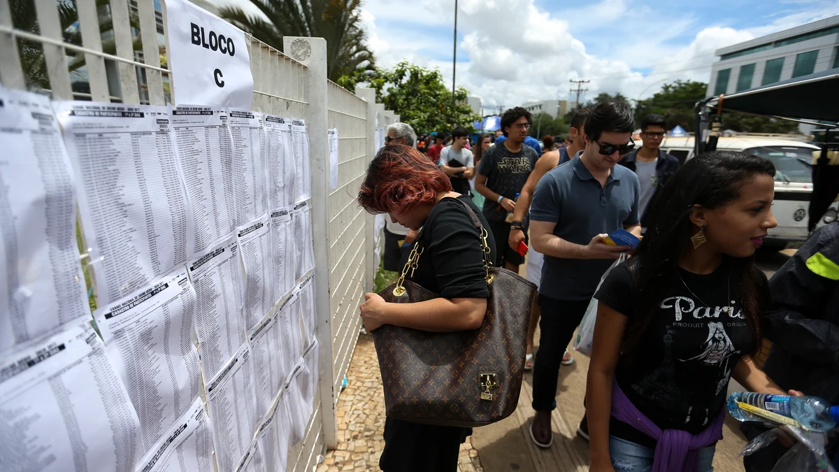 Candidates walk beside posted lists at the entrance to an Enem test site