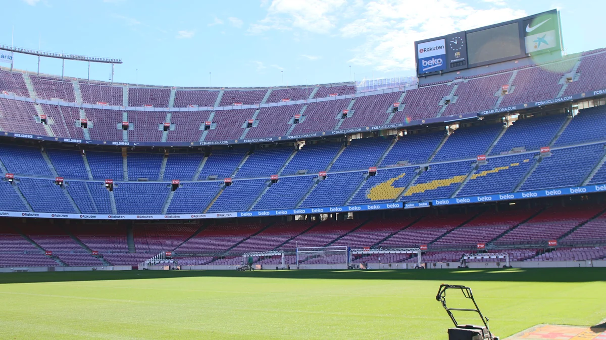 Pelouse et tribunes vides du Camp Nou, avec les lettres FCB en sièges jaunes et un tableau d’affichage au-dessus
