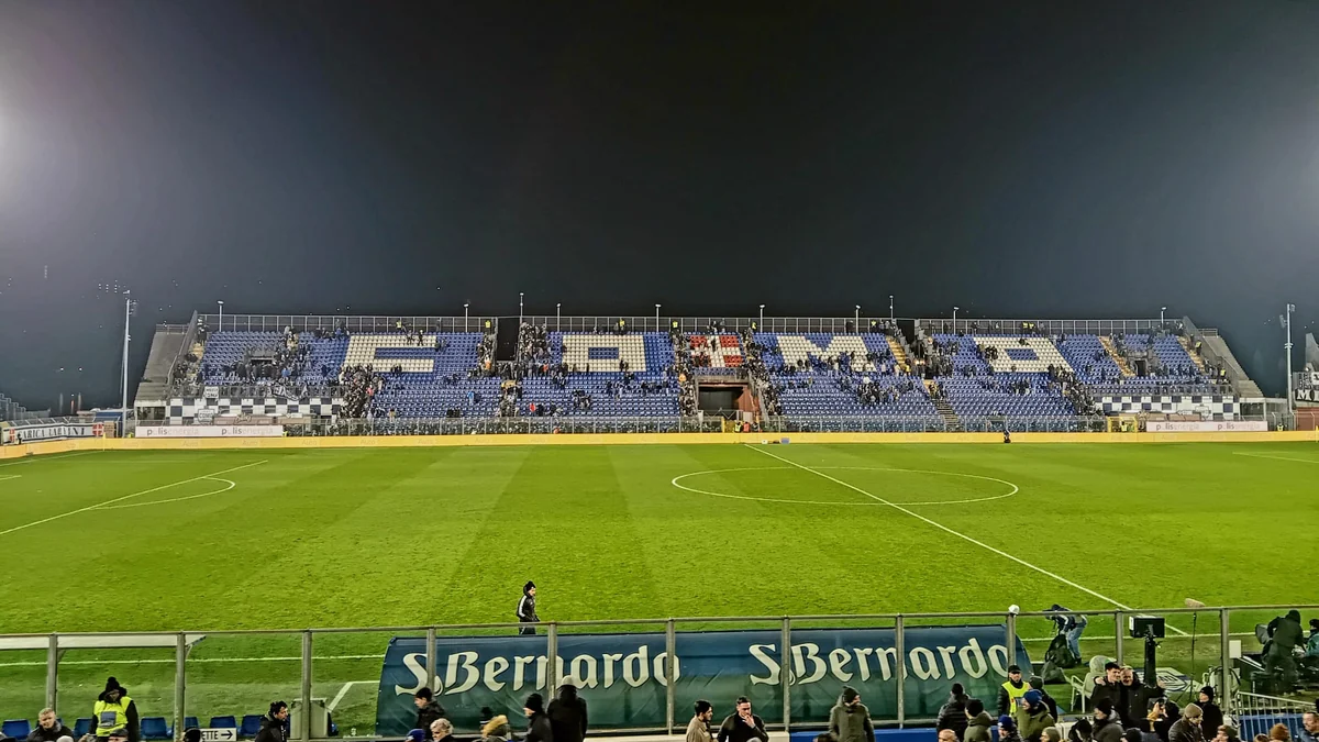 Floodlit pitch and stand with blue seats at Stadio Giuseppe Sinigaglia at night