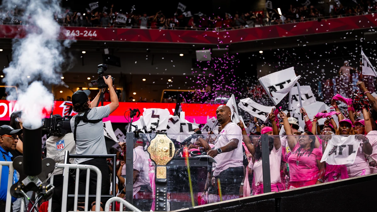 Fans dressed in pink wave flags bearing the letters ATL amid smoke and confetti.