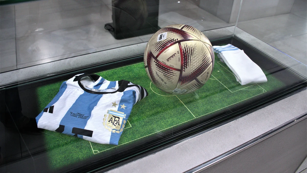 Camiseta a rayas de Argentina, balón y medias expuestos sobre una base verde
