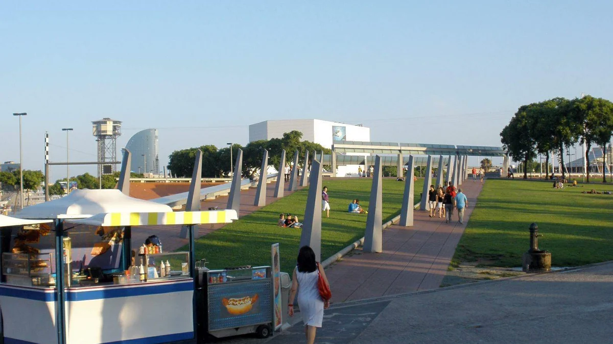 Espace extérieur engazonné du Maremagnum avec des passants et un kiosque au premier plan