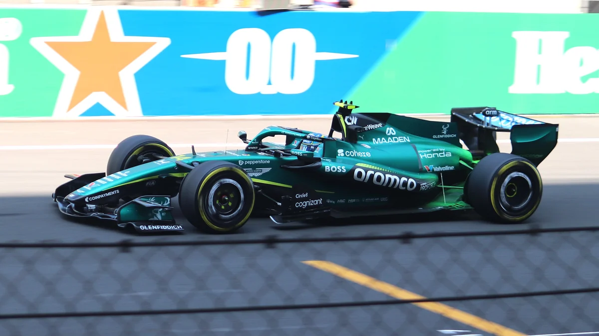 Monoplace verte Aston Martin vue de côté près des barrières du circuit
