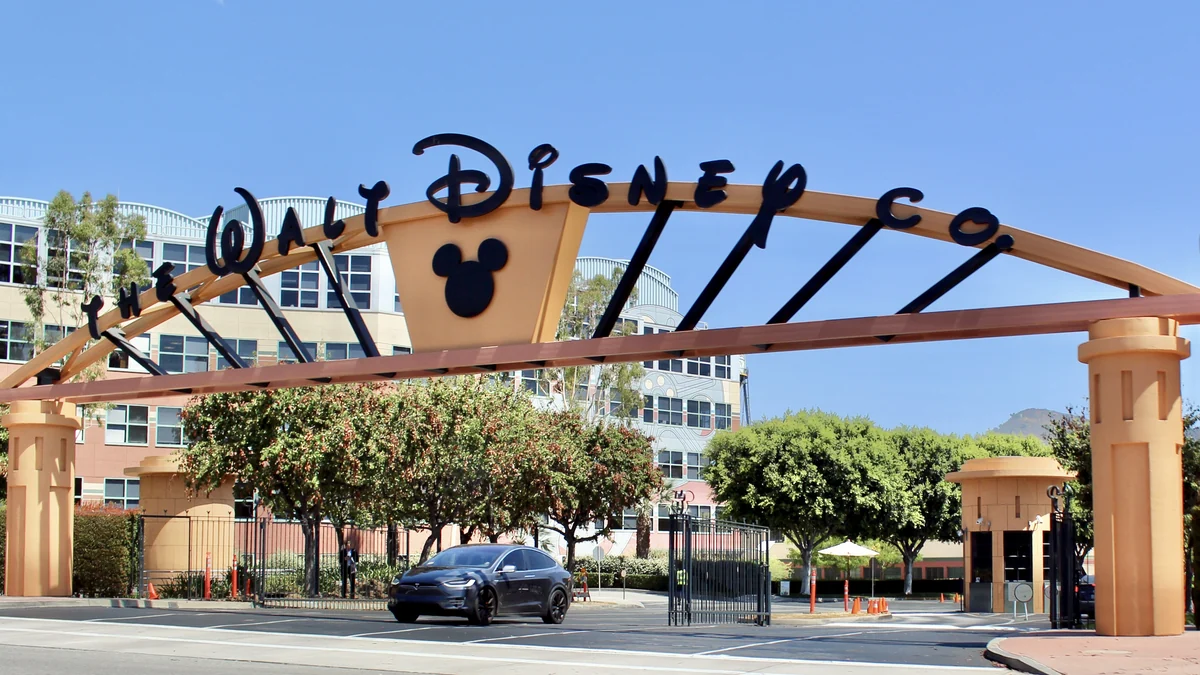 Entrada do Walt Disney Studios sob céu azul, com letreiro no arco e edifícios ao fundo