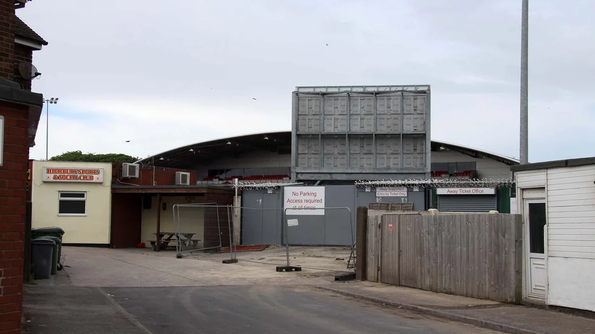 Away entrance at Fleetwood Town’s stadium with gates and a stand behind