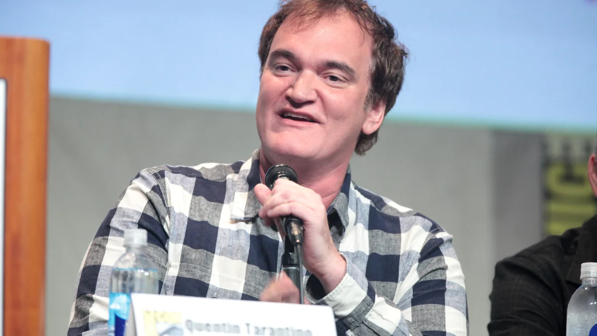 Quentin Tarantino holds a microphone during a public talk.