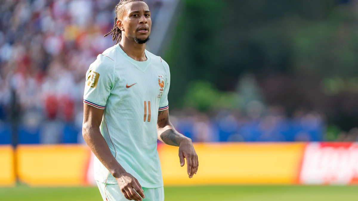 Michael Olise marche sur le terrain avec la tenue claire numéro 11 de la France