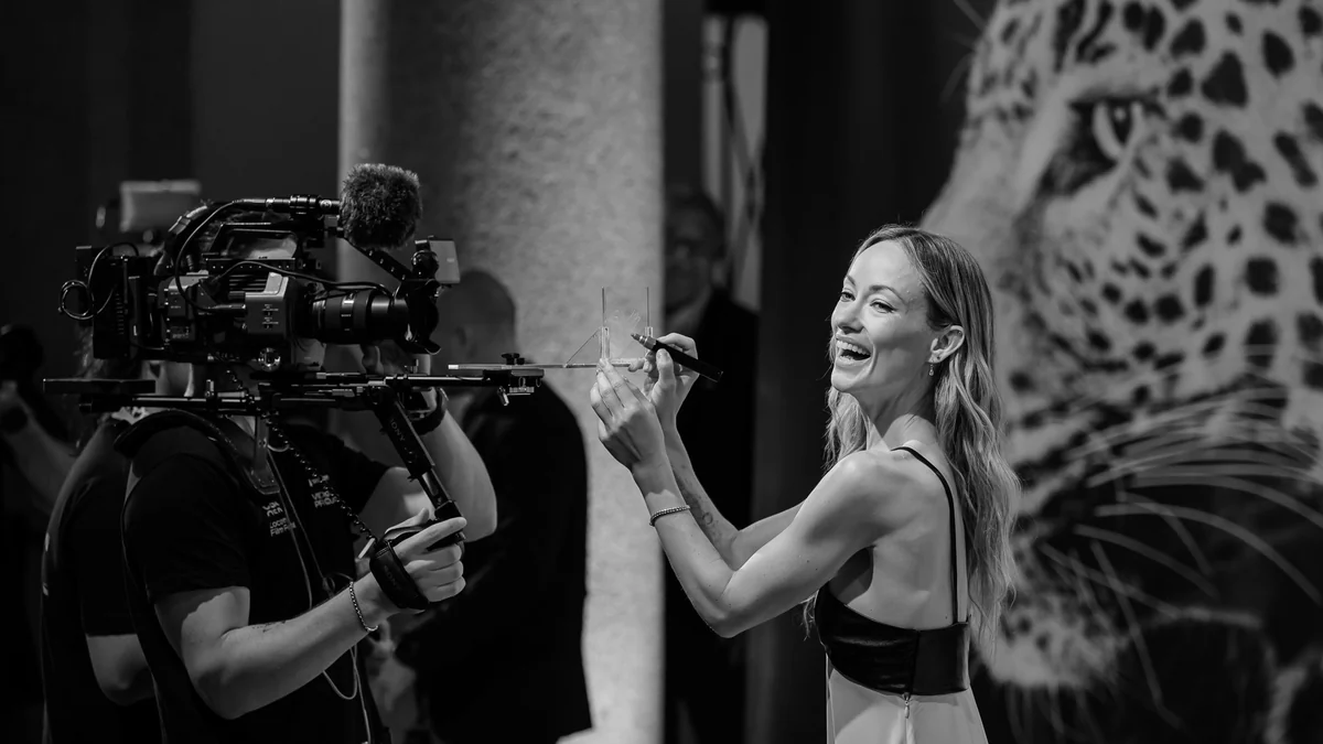 Olivia Wilde sourit devant une caméra sur une photographie en noir et blanc.