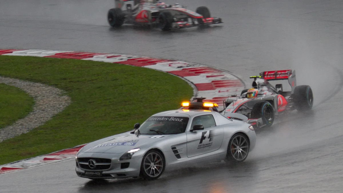 Safety car leading two Formula 1 cars on a wet track