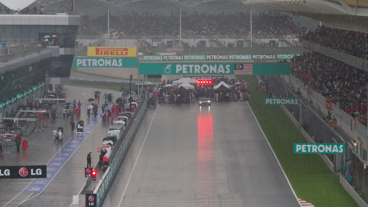 Wet Sepang main straight with cars and teams gathered on the grid