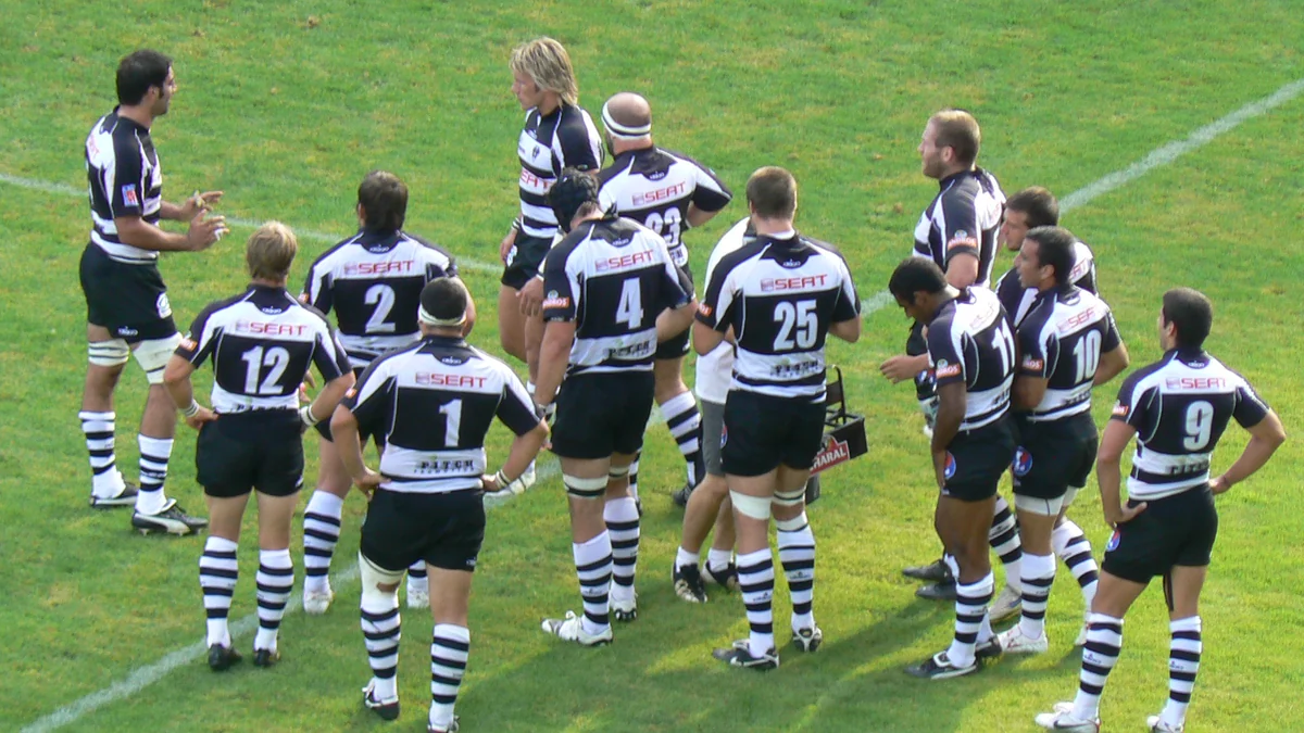 Jogadores do CA Brive reunidos no gramado com uniformes listrados em preto e branco