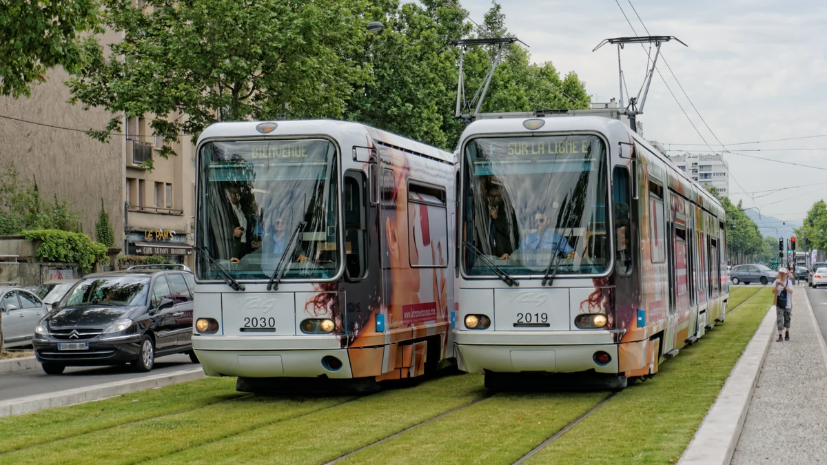 Deux trams côte à côte sur des voies aménagées dans une bande engazonnée