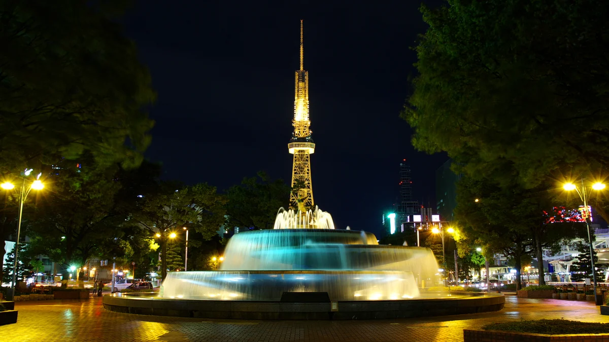 Illuminated tower behind a fountain in Hisaya-odori Park at night