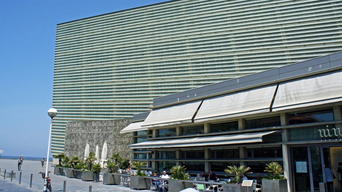 Façade vitrée du Kursaal à côté d’un restaurant avec des tables en terrasse