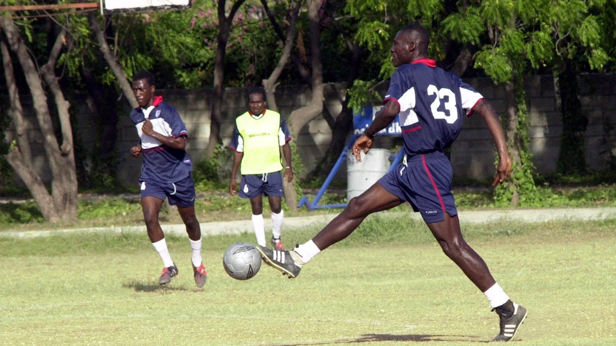 Jugador de Haití con el número 23 controla el balón durante un entrenamiento ante dos compañeros.
