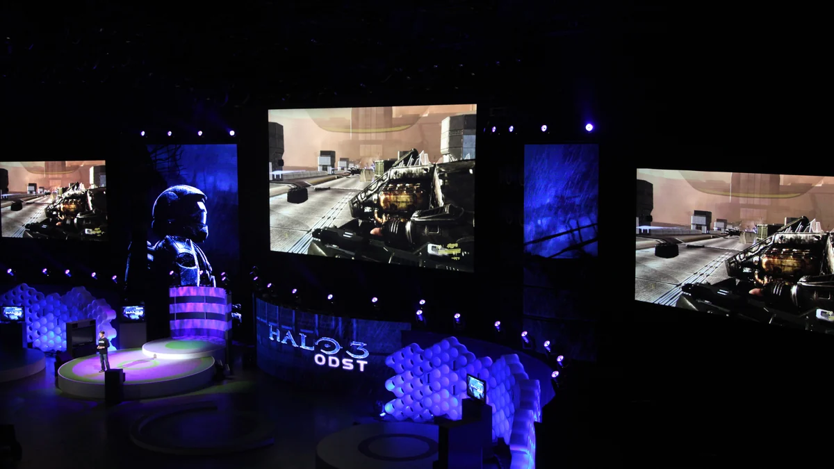 Blue-lit dark stage with screens showing Halo 3: ODST during a presentation