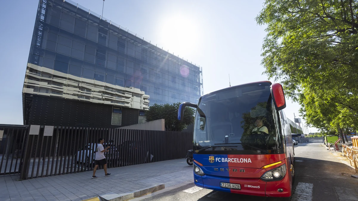 Bus rouge et bleu du FC Barcelone stationné devant un bâtiment sous un soleil intense
