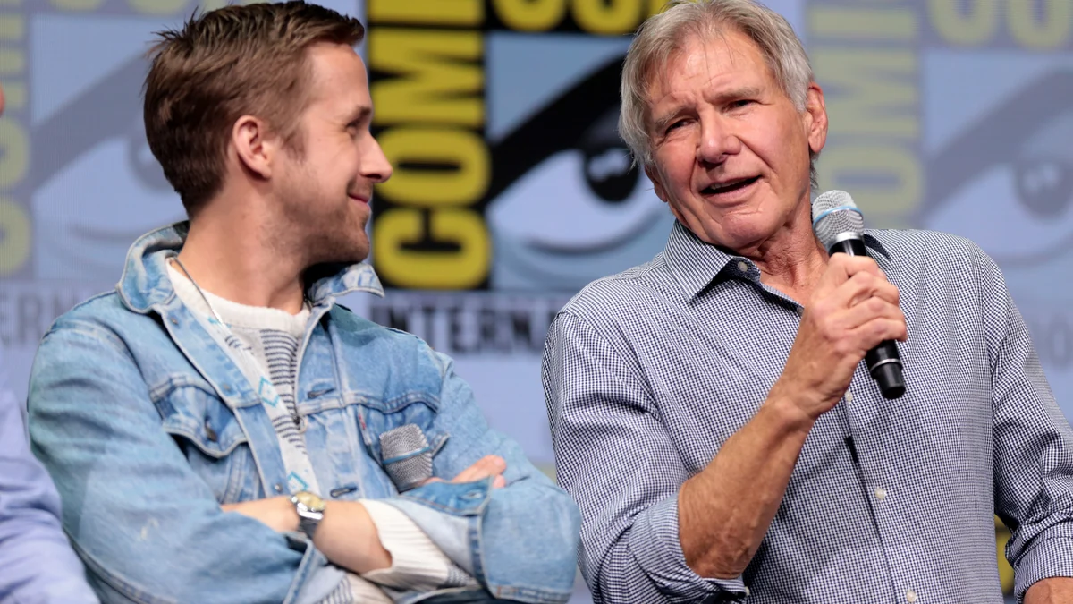 Harrison Ford sonríe y habla con un micrófono junto a Ryan Gosling en un panel.