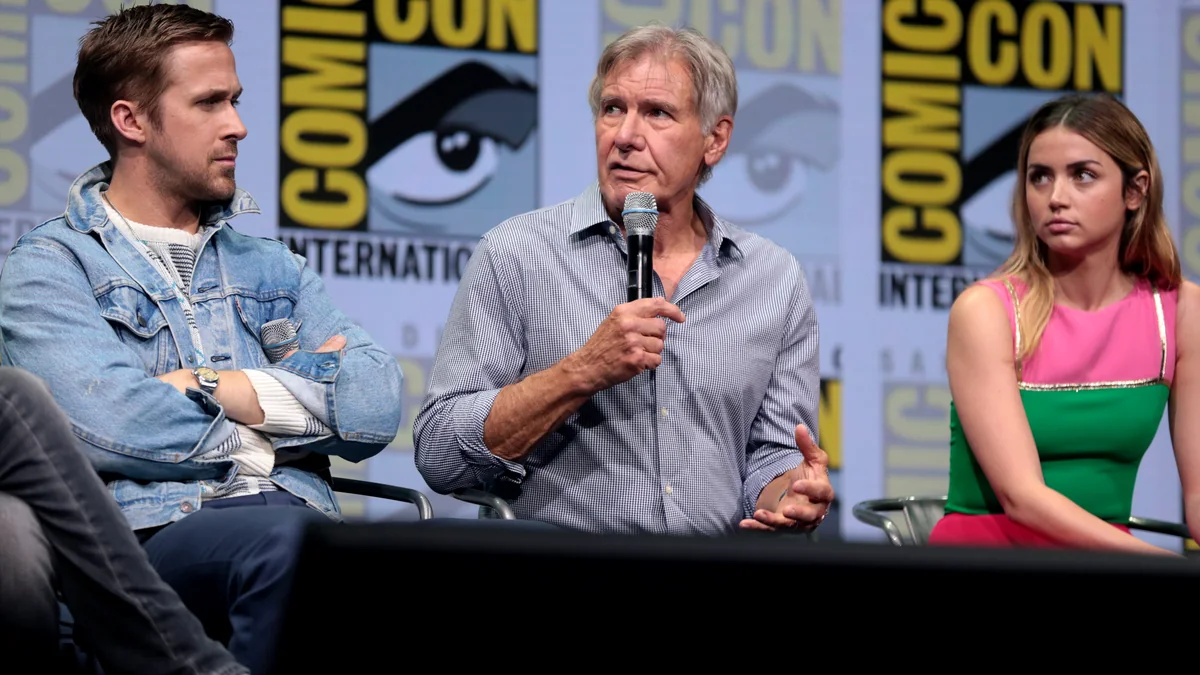Harrison Ford habla con un micrófono entre Ryan Gosling y Ana de Armas en un panel de la Comic-Con.