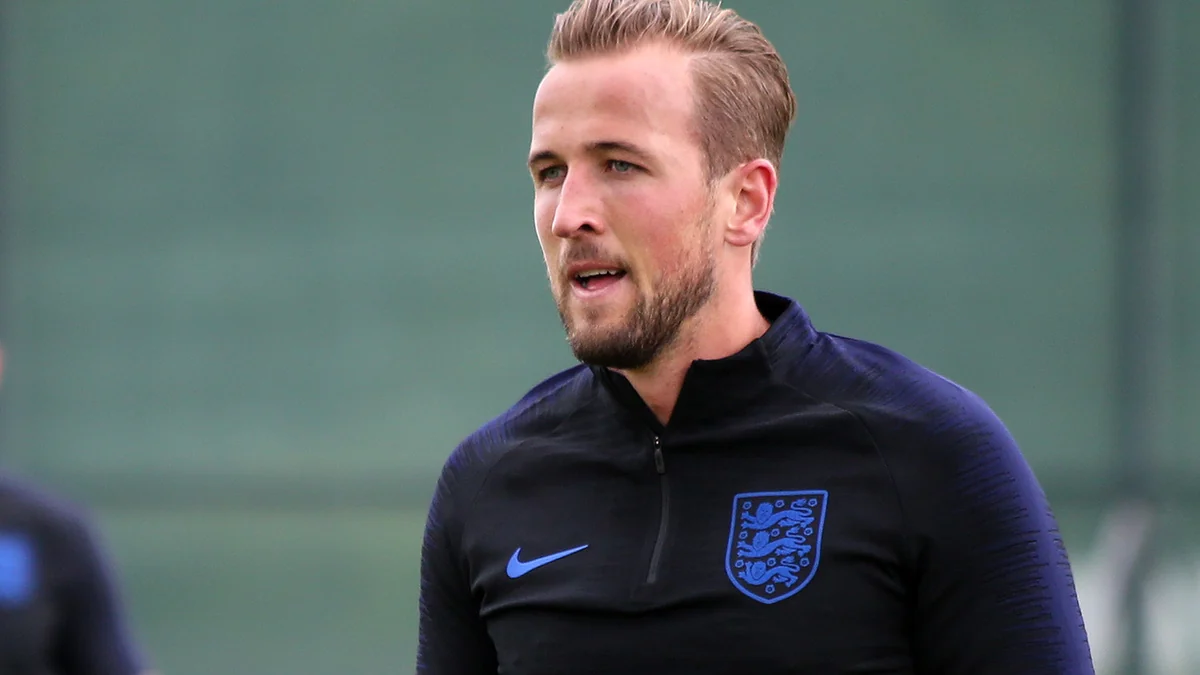 Harry Kane em primeiro plano veste agasalho escuro de treino da seleção da Inglaterra.
