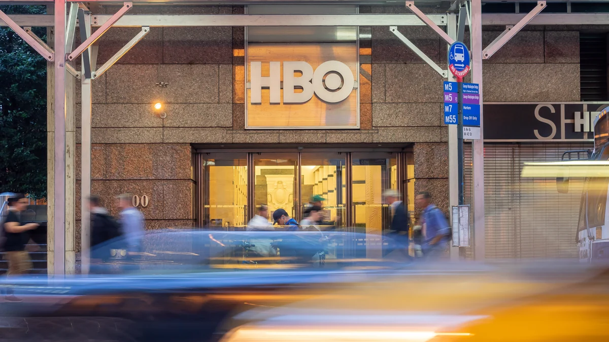 Building facade with an HBO sign, pedestrians, and moving vehicles