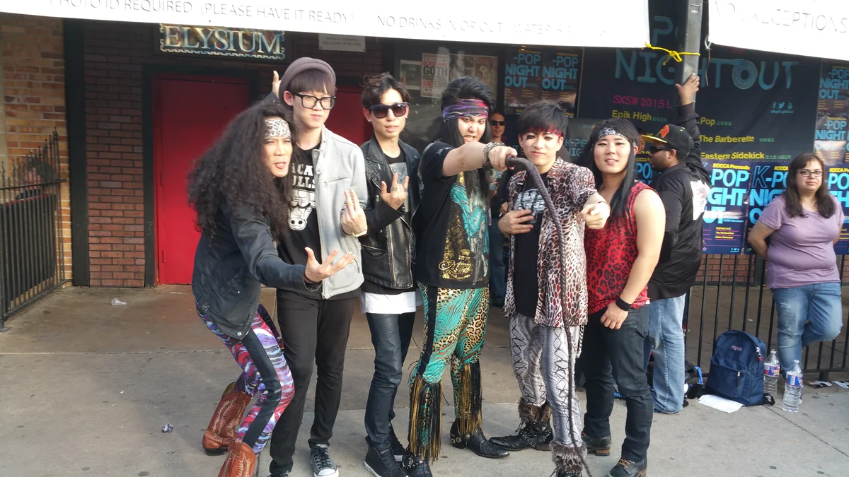 Six membres de groupes posent devant l’entrée d’un événement K-pop à Austin