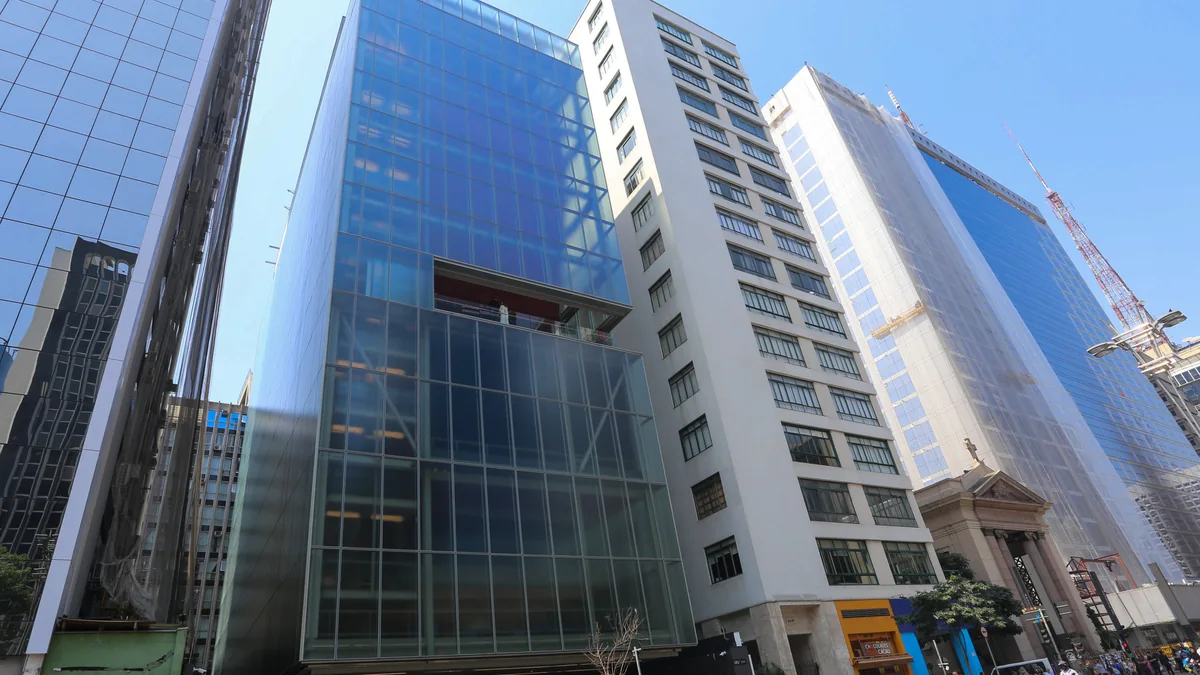Fachada envidraçada do IMS Paulista entre edifícios da Avenida Paulista