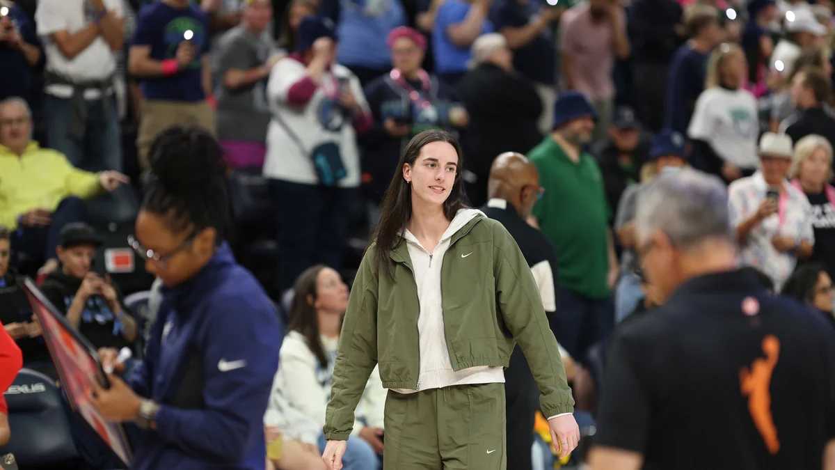 Player in a green tracksuit walks across the court in a crowded arena.