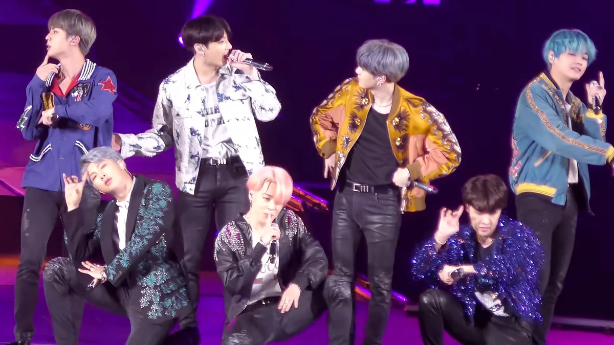 Siete integrantes de BTS en el escenario con micrófonos y vestuario colorido
