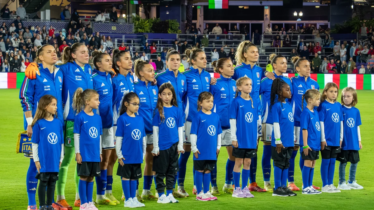 Italy’s women’s football team lines up behind child mascots before a match