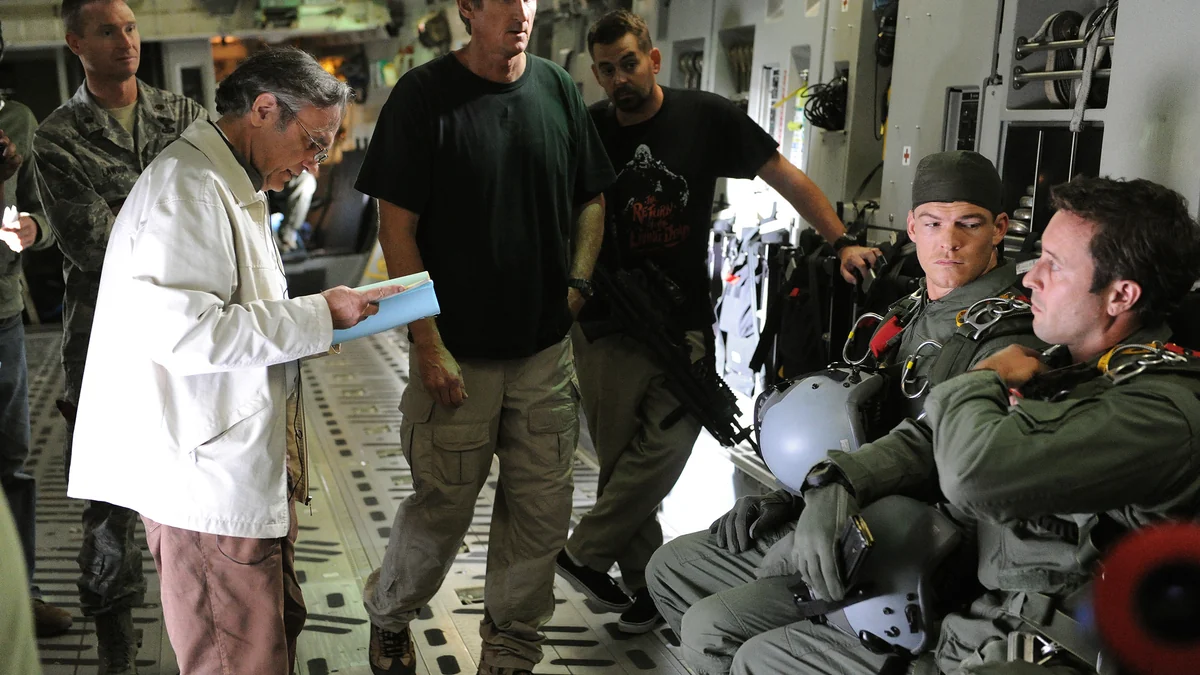 Alan Ritchson e outro ator sentados com equipamentos de voo dentro de uma aeronave, cercados por uma equipe de produção