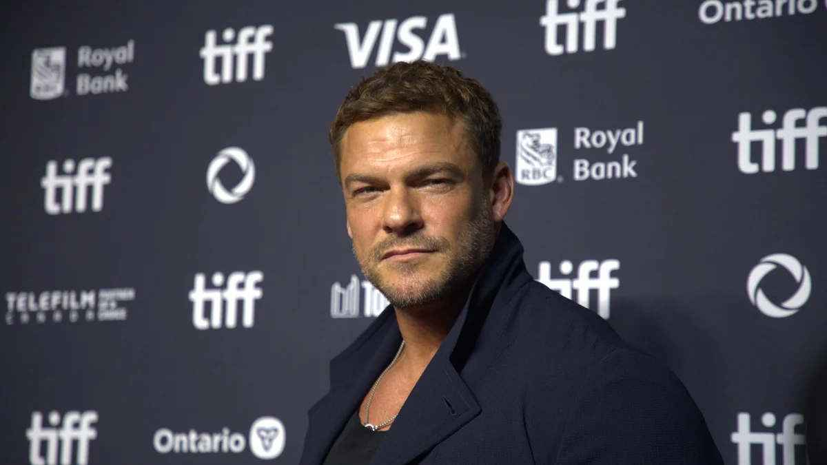Alan Ritchson posa diante de um painel do Festival Internacional de Cinema de Toronto
