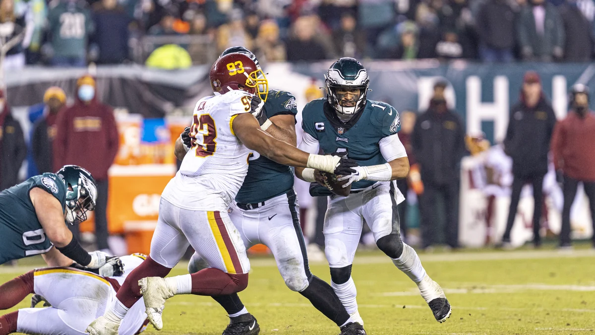 Jalen Hurts segura a bola atrás de um bloqueador dos Eagles durante uma partida