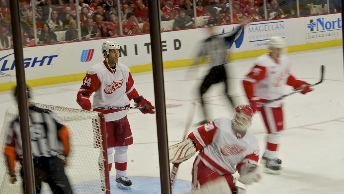 Des joueurs des Detroit Red Wings en blanc et rouge près du but.