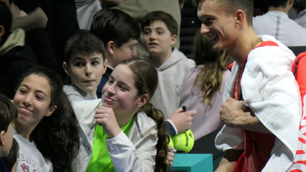 Jiri Lehecka sourit auprès de jeunes supporters tenant des balles de tennis à faire signer